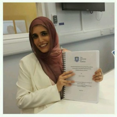 Color photograph of Aishah Al-Shatti smiling and holding a booklet.