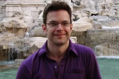 Color image of Dr. Markley wearing a purple button down shirt and glasses.