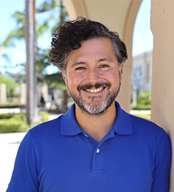 Color photo of Dr. Ivan Ortiz in a bright blue polo in front of a pillar.