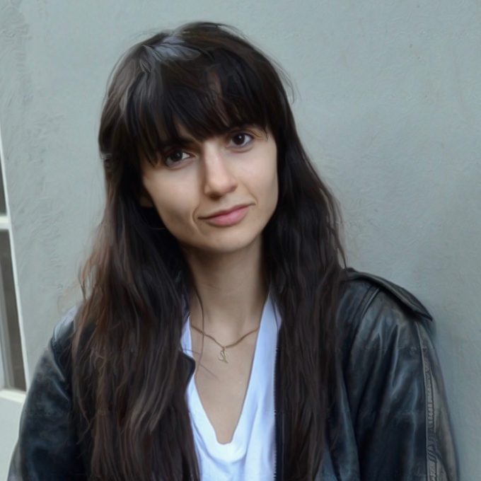 Color photograph of Anahid Nersessian wearing a leather jacket in front of a gray background.
