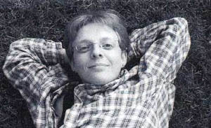 Black and white photo of Shaw with her hands crossed behind her head laying on the ground.