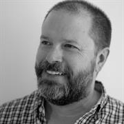 Black and white photo of Andrew Franta in a plaid button down.